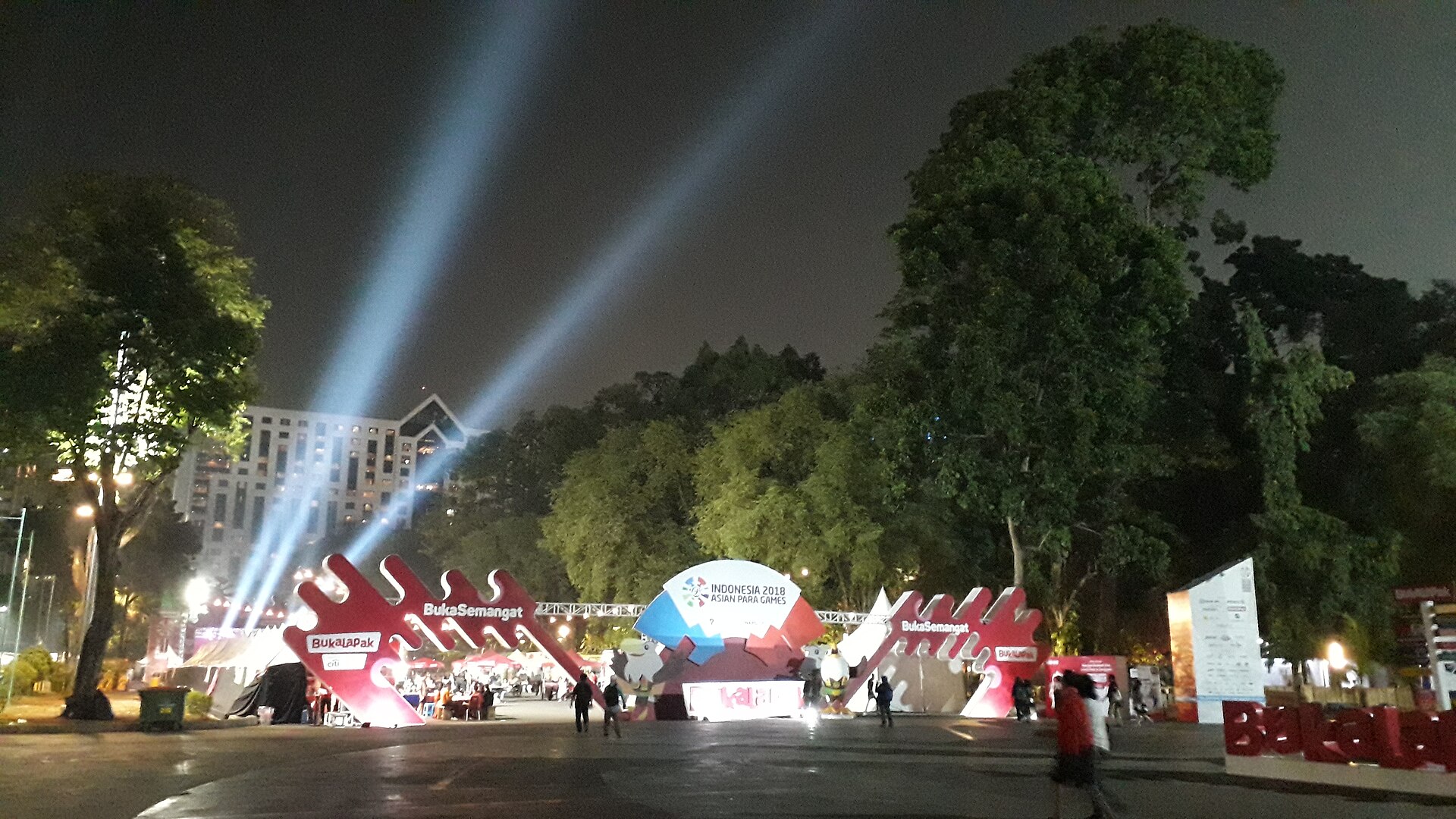 Panggung acara terbuka pada malam hari dengan sorot lampu ke langit